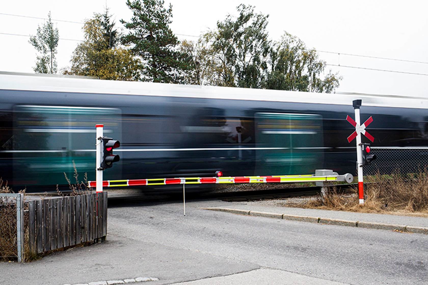 Tog passerer ved en planovergang. Bommen ligger nede. 