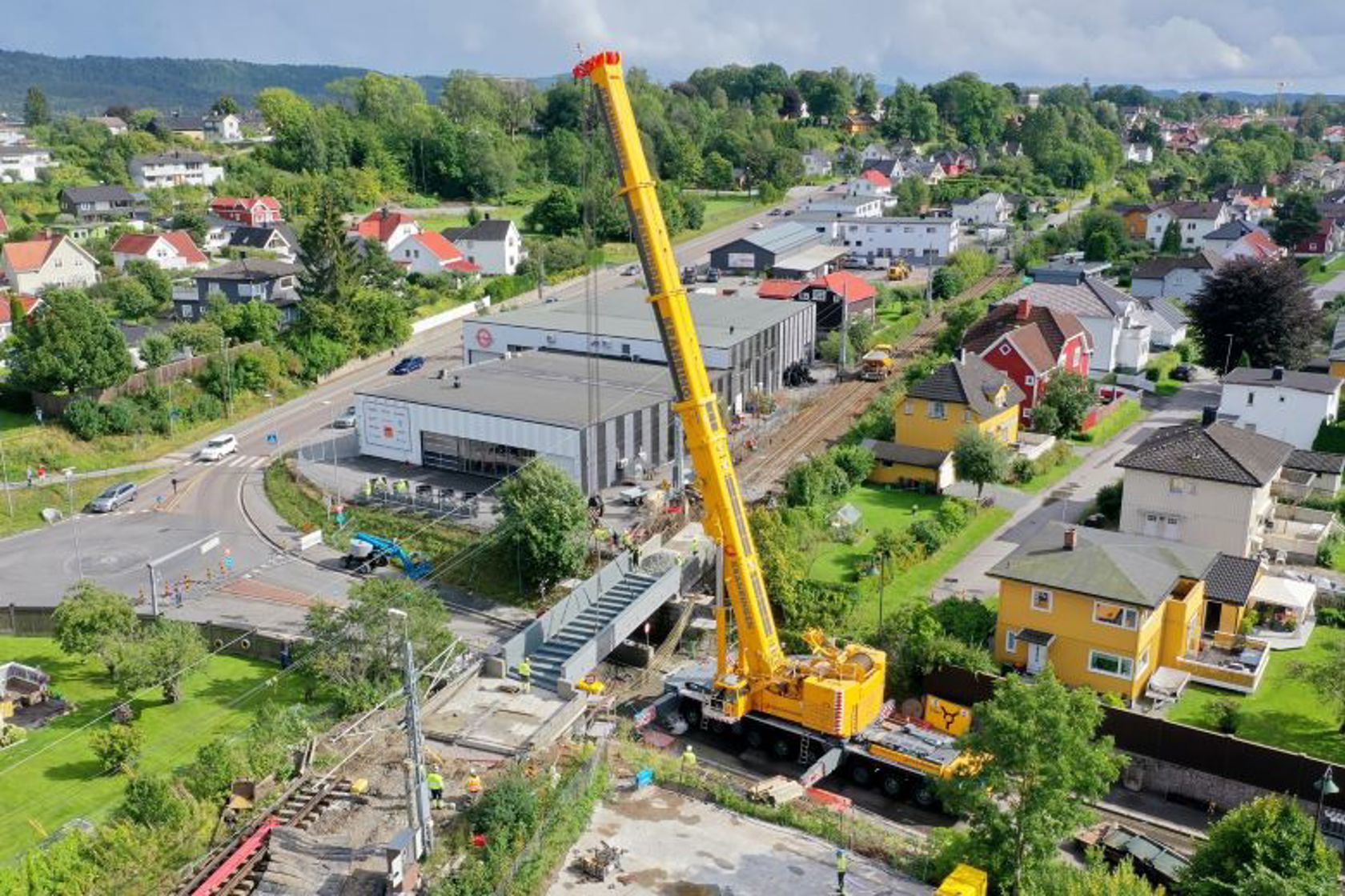 En diger kran heiser en stor bru på plass over et jernbanespor.