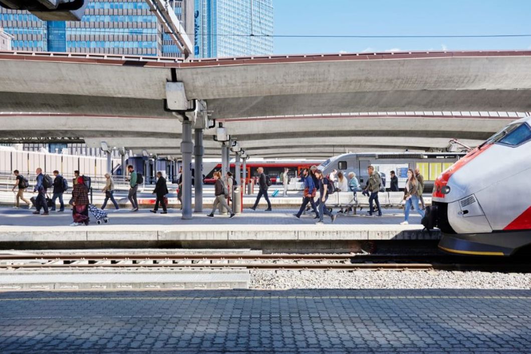 Passasjerer går av et tog og på en plattform på en jernbanestasjon