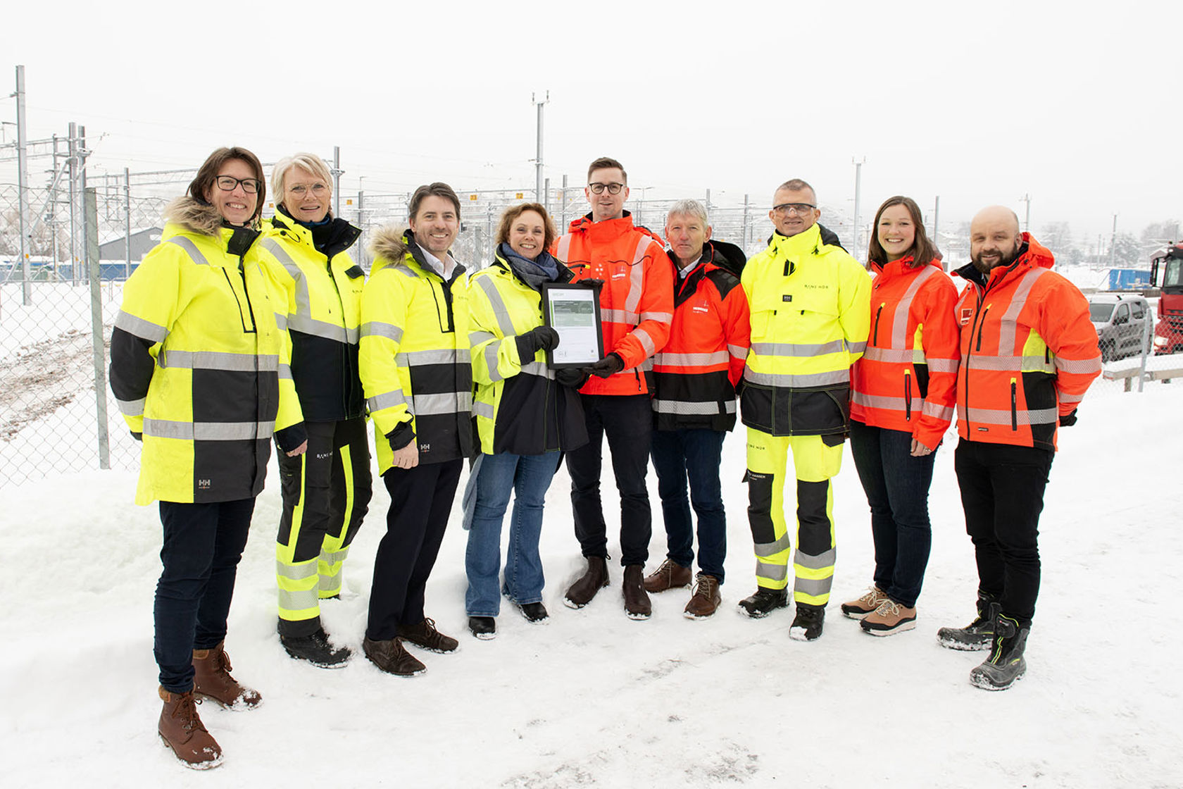 En gruppe mennesker i vernetøy utenfor anleggsområdet. Det er vinter. 