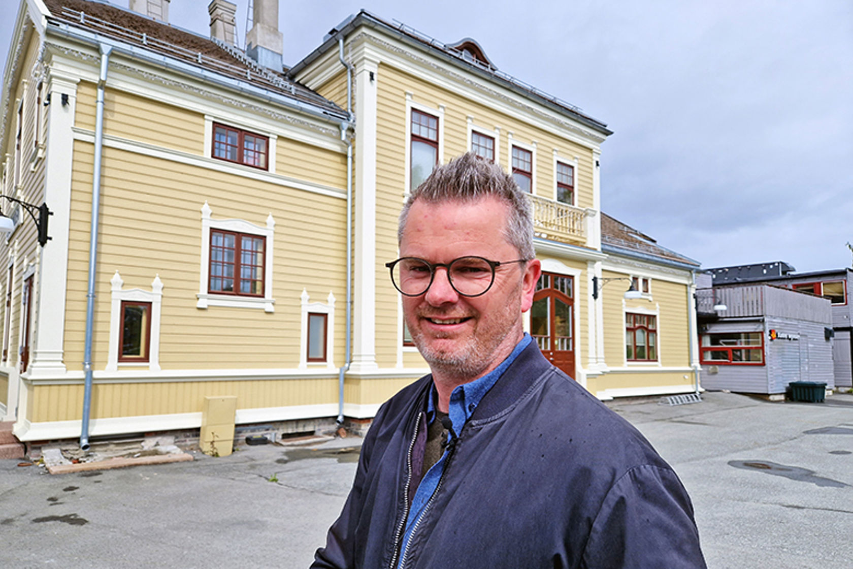 Mann står foran en pen, gammelt trebygning