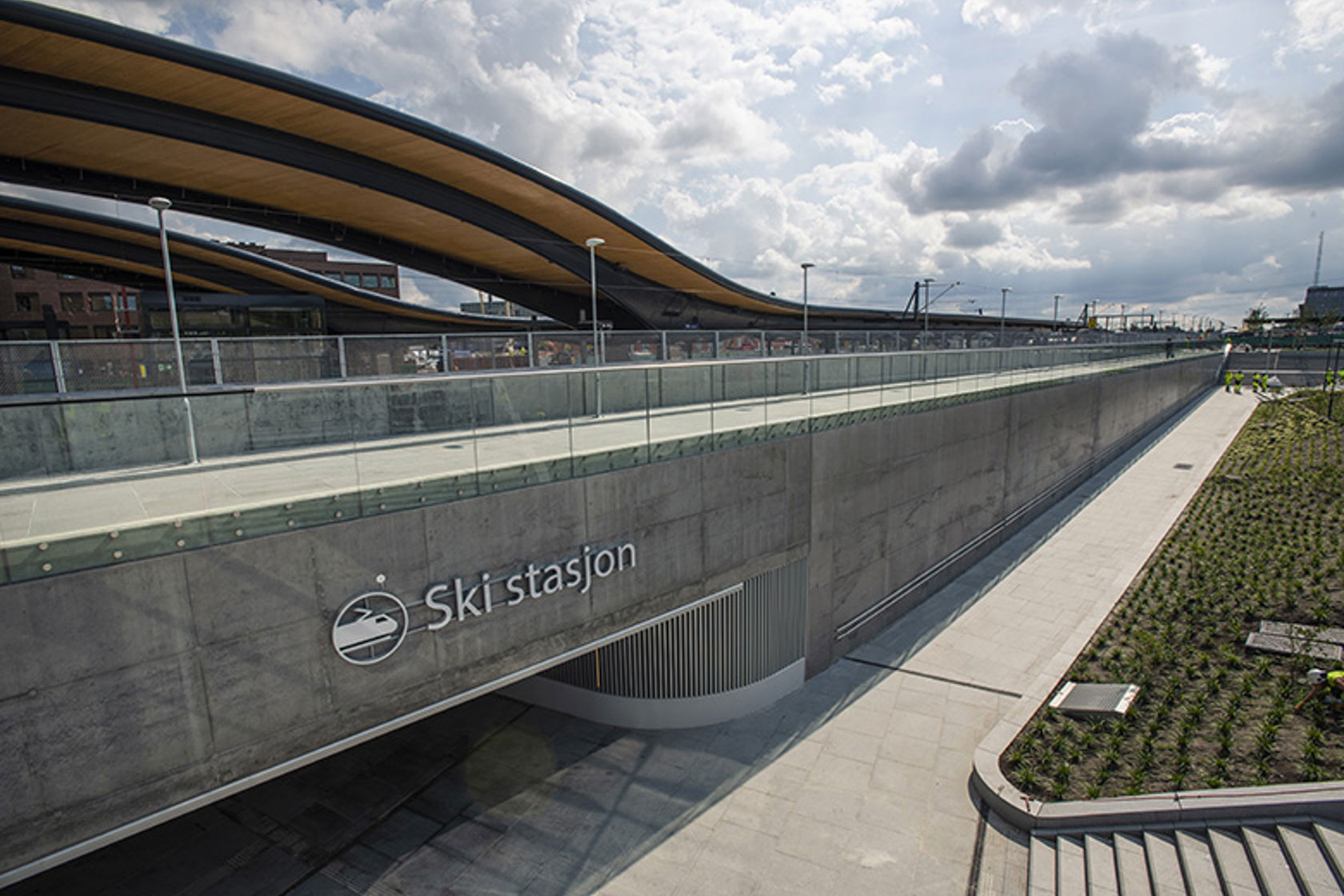 Bildet viser en ny og moderne stasjonsbygning som er bygget i stein, betong og tre.
