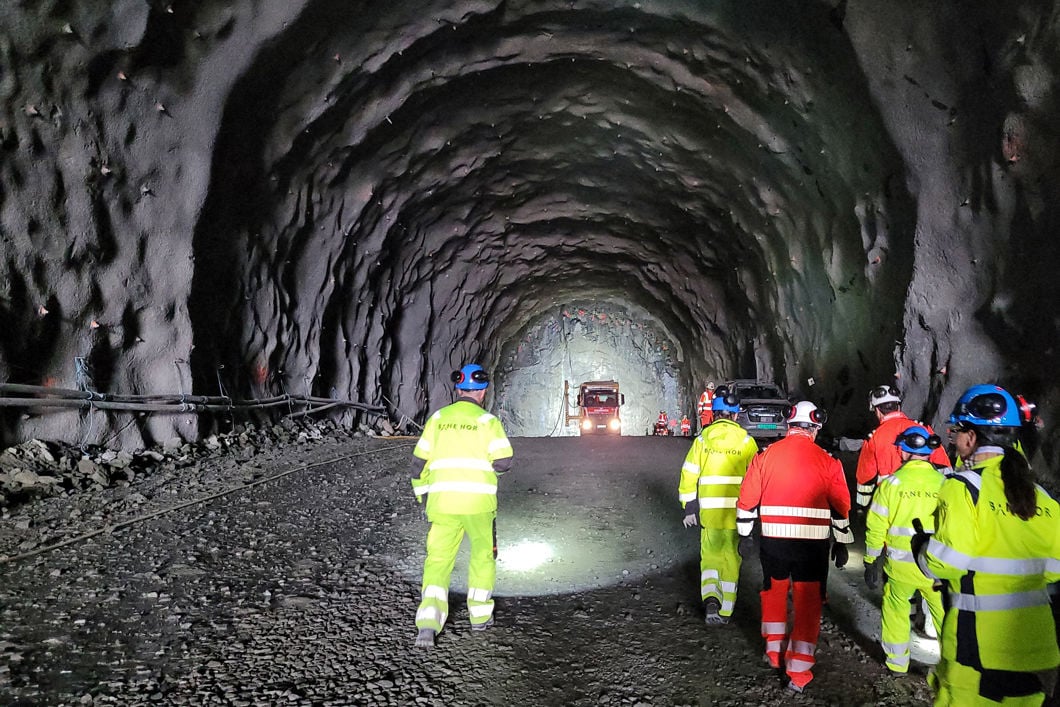 Folk i arbeidsklær går innover i en tunnel