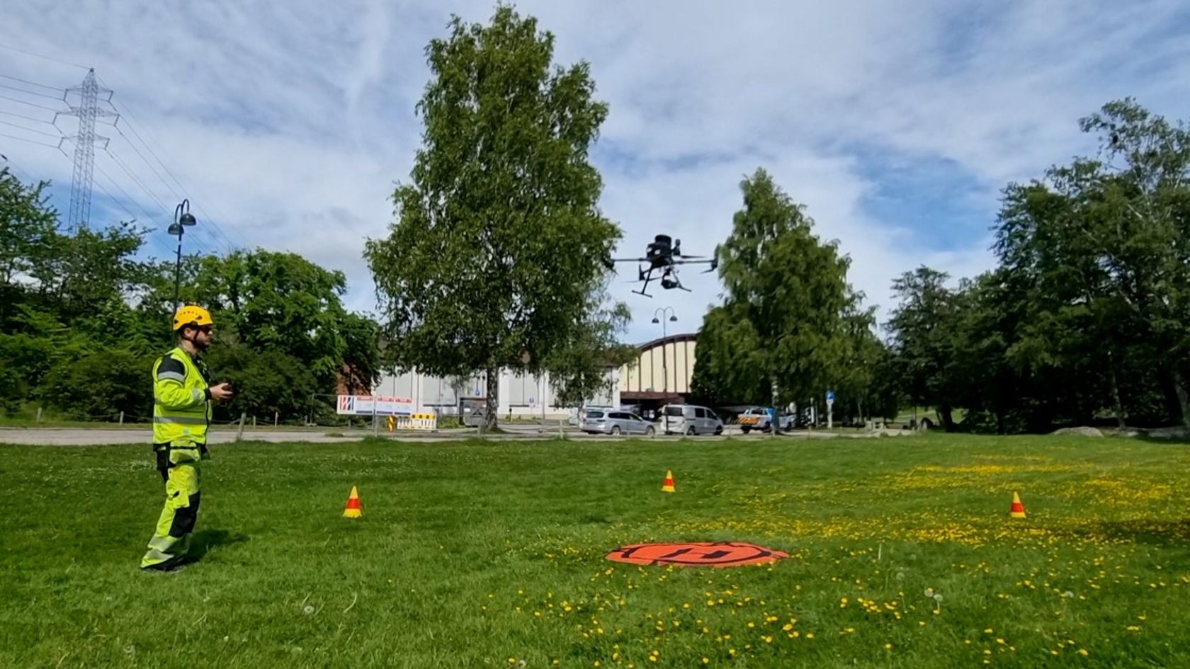 Mann i vernetøy og drone i lufta foran ham.