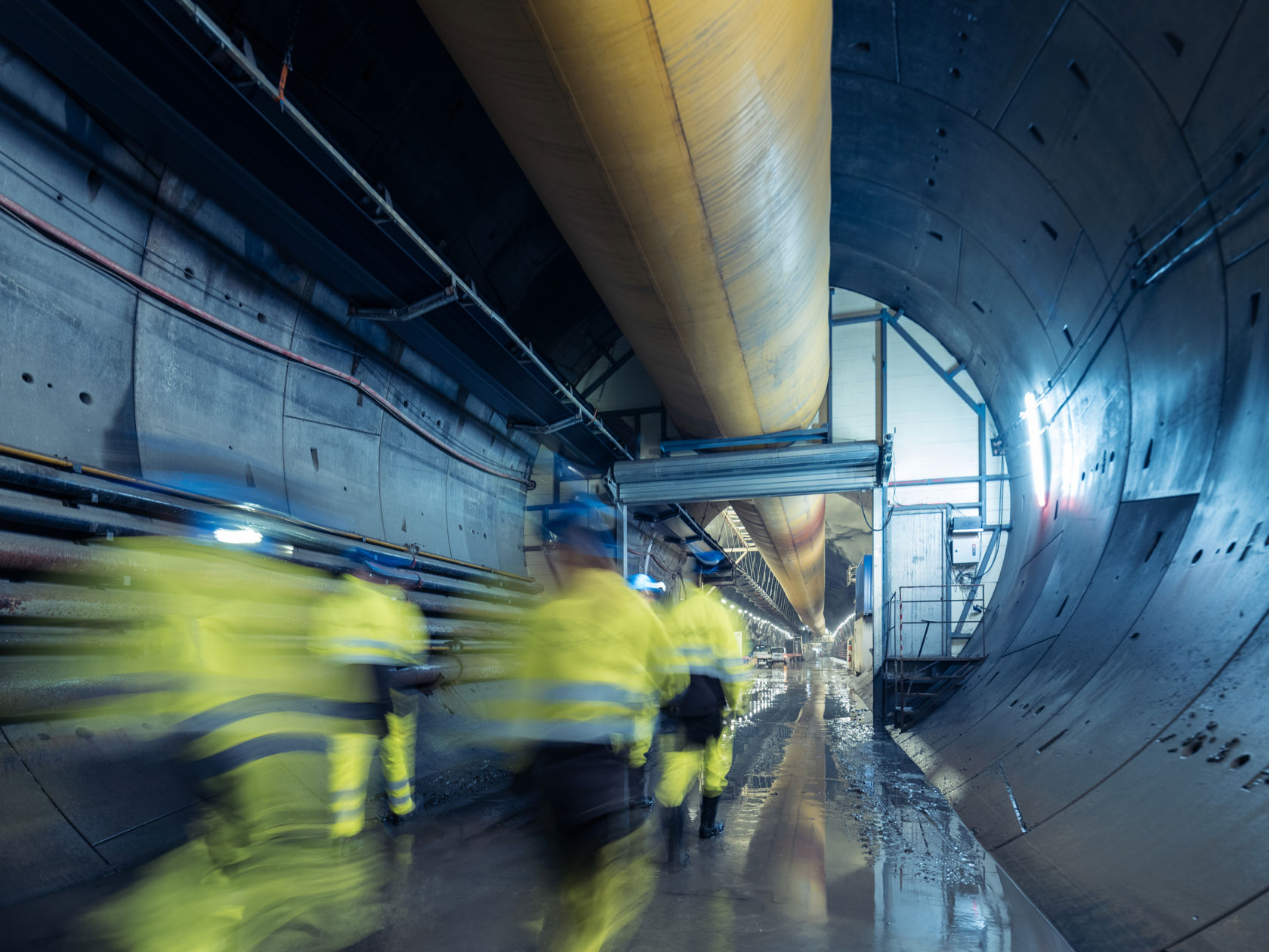 Folk i arbeidsklær går innover i en tunnel.