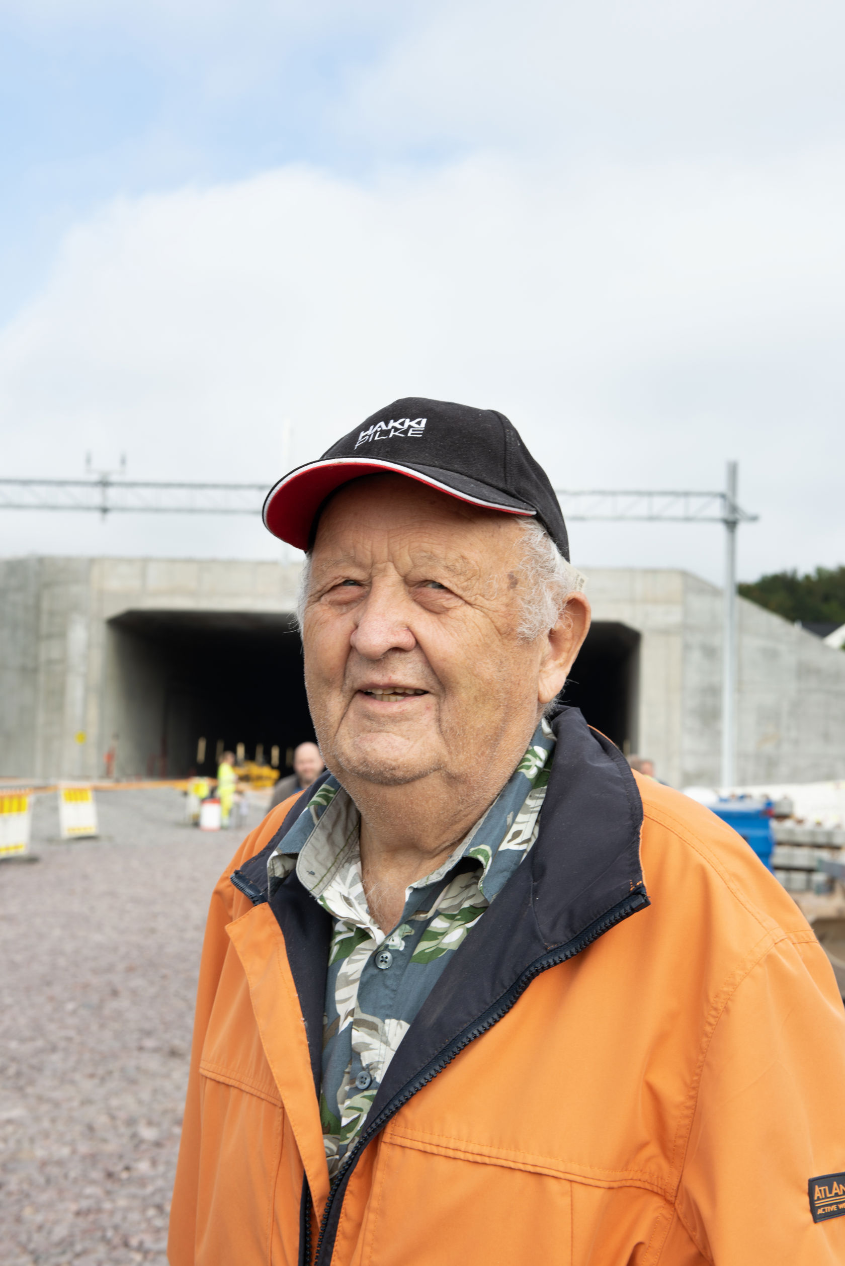 Eldre mann med oransje jakke og svart cap