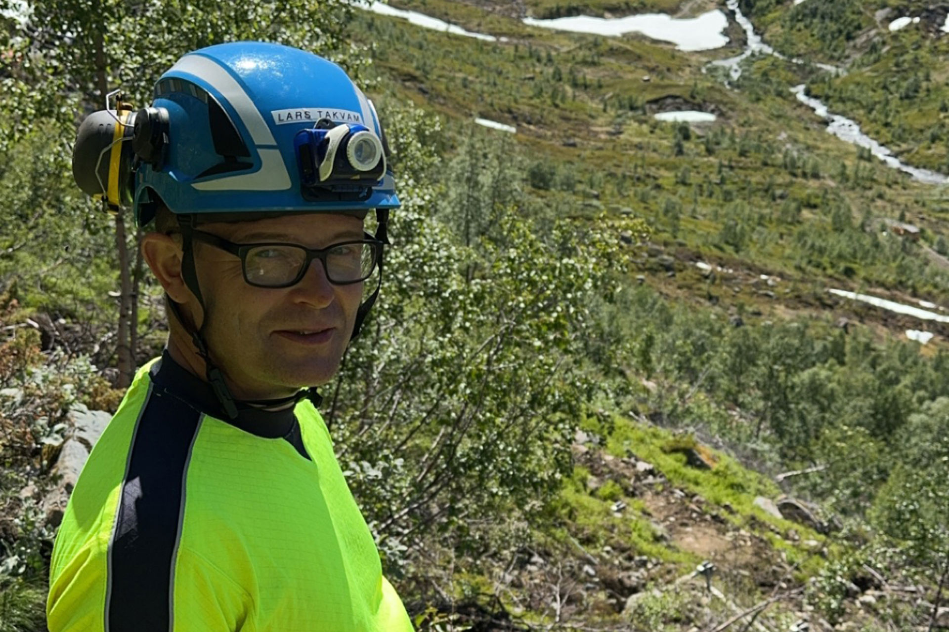 Mann med hjelm i fjellskråning